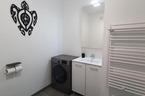 une salle de bain avec une machine à laver et un lavabo dans l'établissement T2 avec Terrasse en ville, proche mer et campagne, à Saint-Nazaire