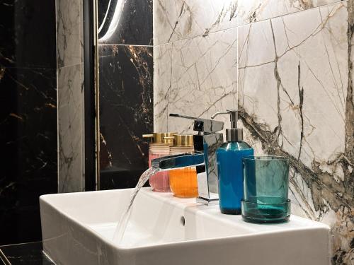 a bathroom sink with a bottle of soap and a glass at Grand Viceroy Apartments - Gothic Tower View in Prague