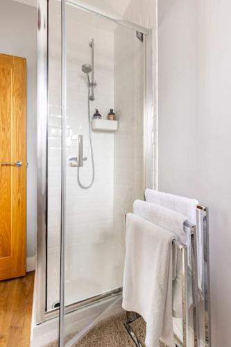 a bathroom with a shower with white towels on a chair at Castell Bach in Llangollen