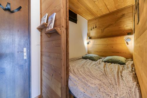 - une chambre avec un lit et un mur en bois dans l'établissement Homency - Résidence le Majestic N2, à L'Alpe-d'Huez