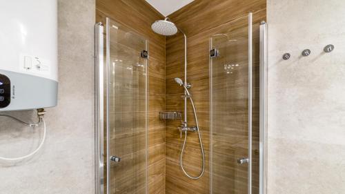 a shower with a glass door in a bathroom at ENKLAWA Apartamenty Piamola in Krynica Morska