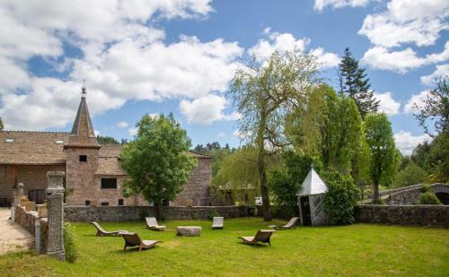 a yard with chairs and a church at Gites de france 24 personnes - domaine de coulagnettes in Serverette