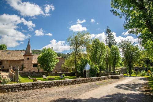 a road in front of a stone building with a church at Gites de france 24 personnes - domaine de coulagnettes in Serverette