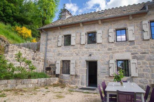 a stone house with a table in front of it at Gites de france 24 personnes - domaine de coulagnettes in Serverette