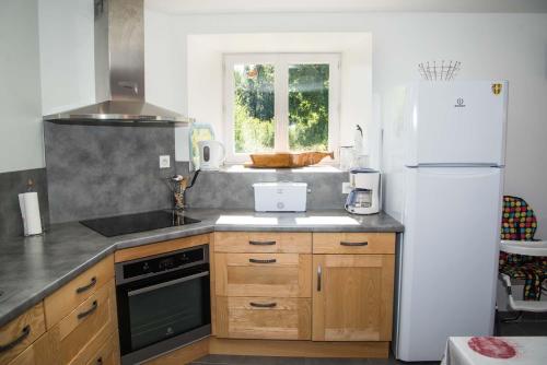 a kitchen with wooden cabinets and a white refrigerator at Gîte Le Moulin de la Vaissière 5/6 personnes in Pierrefiche