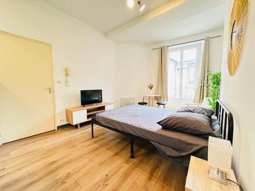 a bedroom with a bed and a desk and a television at Studio Cosy centre historique in Laon