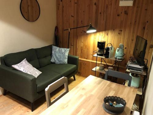 a living room with a green couch and a table at Petite maison à la mer in Fort-Mahon-Plage