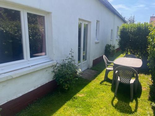 a yard with a table and chairs and a window at Petite maison à la mer in Fort-Mahon-Plage