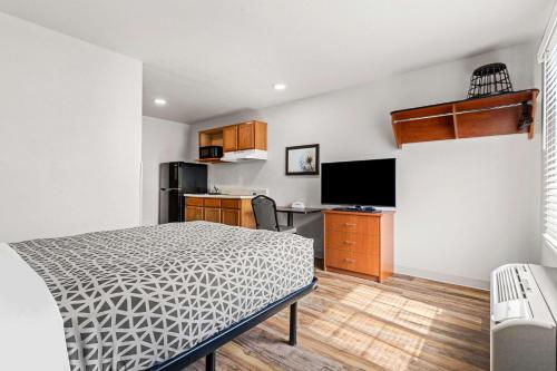 a bedroom with a bed and a desk and a kitchen at WoodSpring Suites Tulsa in Tulsa