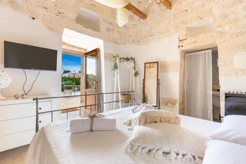 a bedroom with a large bed and a tv at Trullo DoMi by Perle di Puglia in Noci