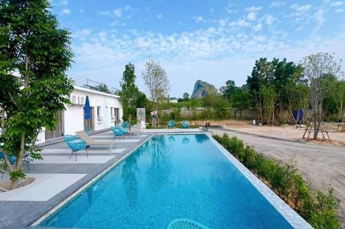 a swimming pool with blue chairs next to a house at Khao Chi Chan Resort in Ban Nong Chap Tao