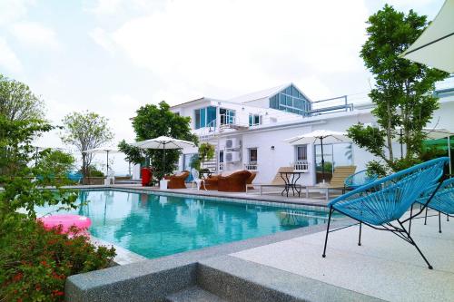a swimming pool with blue chairs and a house at Khao Chi Chan Resort in Ban Nong Chap Tao