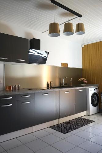 a kitchen with black cabinets and a washing machine at La VOLCANAISE in Village Sainte Anne