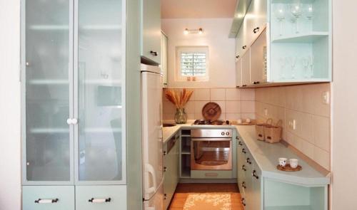 a small kitchen with white cabinets and a refrigerator at Casa di Campara in Neum