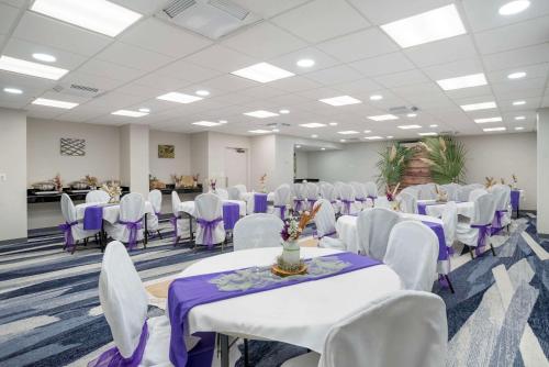 a room with white tables and white chairs and purple tables at Comfort Inn & Suites New Orleans Airport North in Kenner