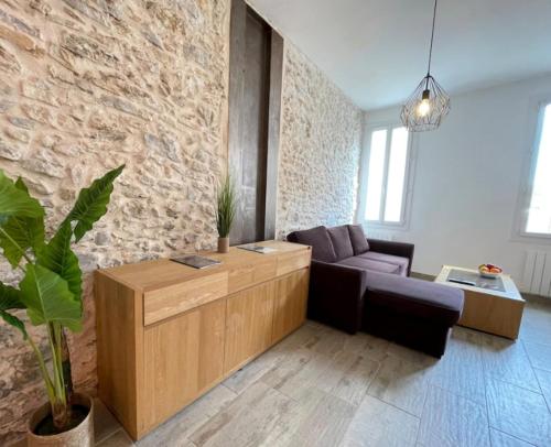 un salon avec un canapé et un mur en pierre dans l'établissement Atelier des rêvesVieuxPortProche PlagesLaCiotat, à La Ciotat