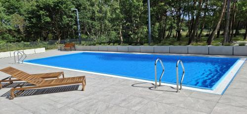 ダルウフコにあるApartament Morski Widok NAUTIC PARK 51 Darłówkoのスイミングプール(椅子、ベンチ付)