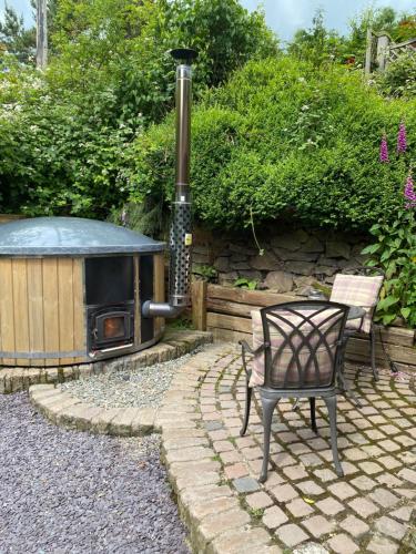 a patio with a chair and an outdoor stove at Romantic Cottage with Wood-fired Hot tub and Outdoor Pizza Oven in Shrewsbury