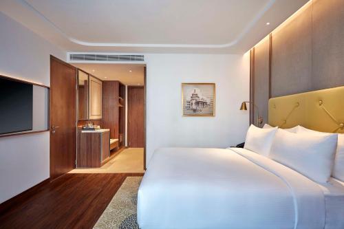 a bedroom with a large white bed and a bathroom at Doubletree By Hilton Bengaluru Whitefield in Bengaluru