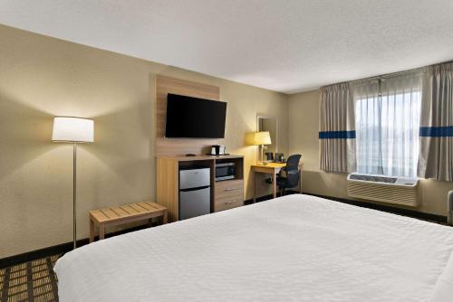 a hotel room with a bed and a flat screen tv at Clarion Pointe Bloomington-Normal near I-55 and University in Bloomington
