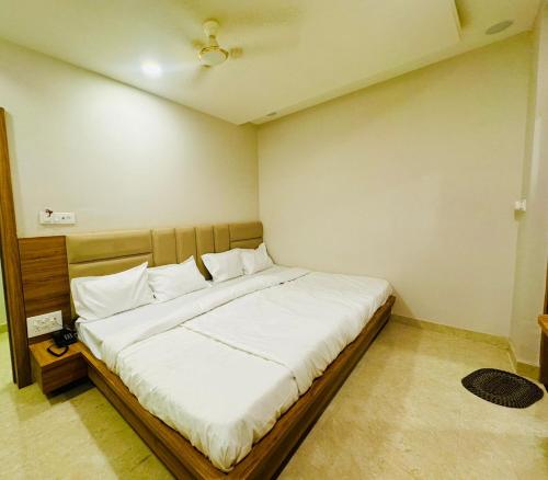 a bedroom with a large bed with white sheets at Hotel Najaf Palace in Ajmer