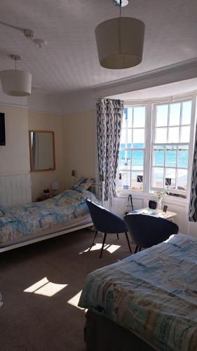 a bedroom with two beds and a table and chairs at Lyndale Guest House in Weymouth