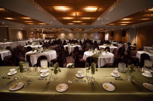 a large banquet hall with tables and chairs with white table settings at Edmonton Hotel & Convention Center Edmonton in Edmonton