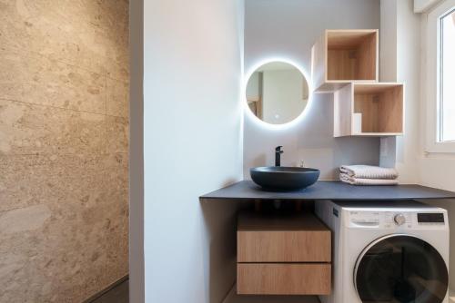 une salle de bain avec une machine à laver et un lavabo dans l'établissement Le Petit Prince, standing & vue mer, à Boulogne-sur-Mer