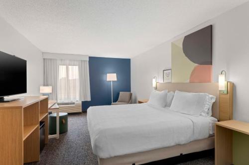 a hotel room with a bed and a flat screen tv at Spark By Hilton Newcomerstown in Newcomerstown