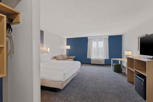 a hotel room with a bed and a flat screen tv at Spark By Hilton Newcomerstown in Newcomerstown