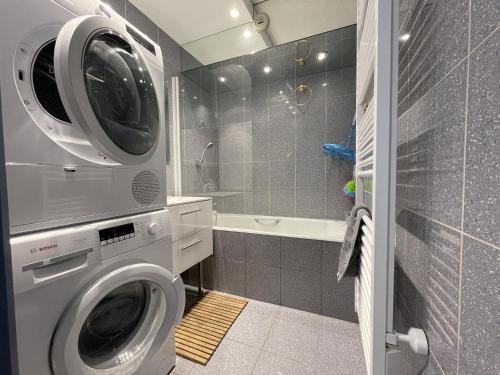 une machine à laver dans une salle de bain avec douche dans l'établissement Homency - Résidence Chalet des Roches 32, à L'Alpe-d'Huez