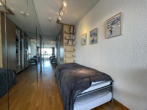 une chambre avec un lit et une paroi vitrée dans l'établissement Homency - Résidence Chalet des Roches 32, à L'Alpe-d'Huez