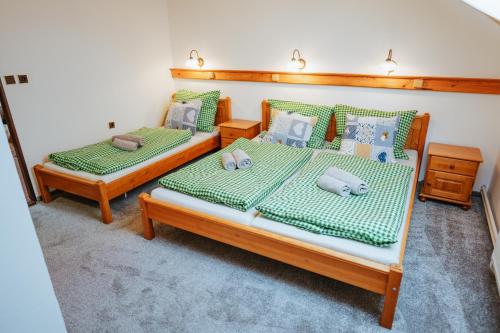 two beds in a bedroom with green and blue pillows at Lichkovská chalupa in Lichkov