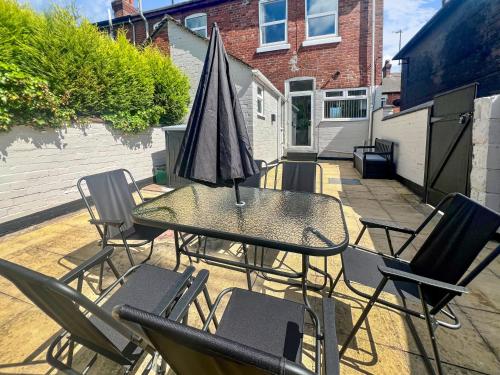 a table and chairs with an umbrella on a patio at Stylish House Near Hospital with Free Parking in Stoke on Trent