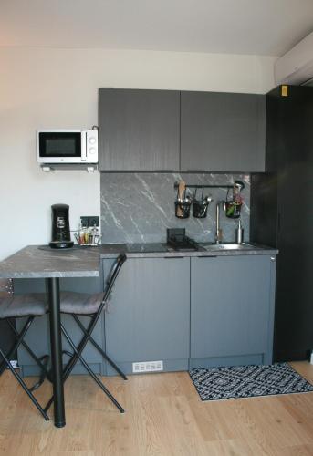 - une cuisine avec un comptoir, un évier et une table dans l'établissement Studio Les Deux Grenouilles 5mn de Colmar, à Herrlisheim-près-Colmar