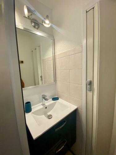 une salle de bain avec un lavabo et un miroir dans l'établissement Vacances à Narbonne Plage !, à Narbonne