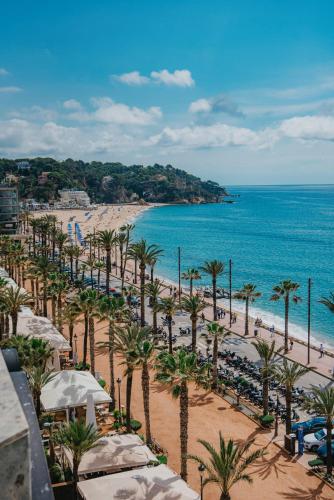 a view of a beach with palm trees and the ocean at Hotel Miramar in Lloret de Mar