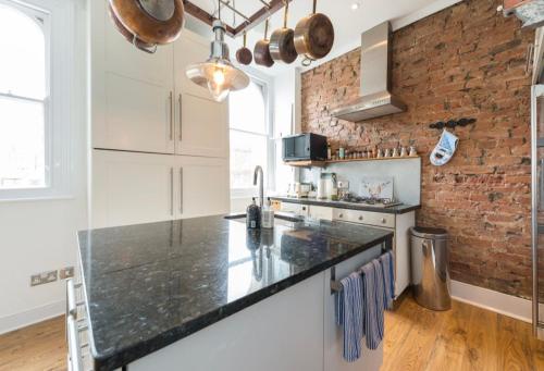 a kitchen with white appliances and a brick wall at Ramsgate Retreat in Kent