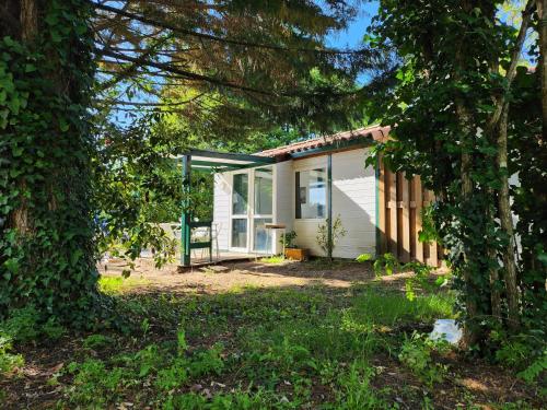 une petite maison blanche avec une véranda et des arbres dans l'établissement Petits Chalets D'Herm, à Herm