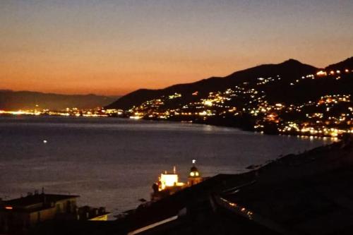 a view of a city and the water at night at attico spettacolare vista mare in Camogli