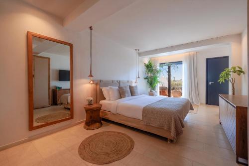 a bedroom with a large bed and a mirror at Asty Mykonos Hotel & Spa - World of One Hotel Group in Mýkonos City