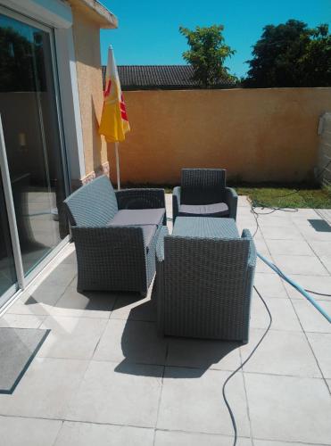 quatre chaises en osier et un parasol sur une terrasse dans l'établissement Maison familiale, à Eaunes