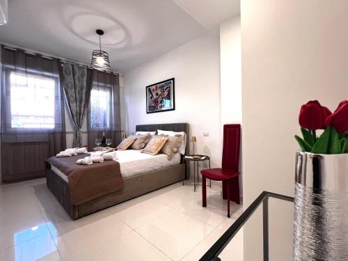a bedroom with a bed and a vase of red flowers at ROMA AIRPORT SKY Apartments in Fiumicino
