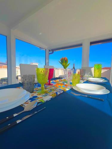 a blue table with plates and glasses on top of it at ROMA AIRPORT SKY Apartments in Fiumicino