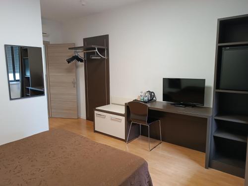 a room with a desk with a computer and a television at Tiby Hotel in Modena