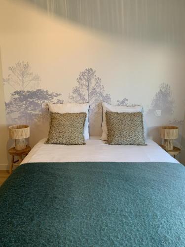 - une chambre dotée d'un grand lit avec des draps verts et blancs dans l'établissement La cabane, à Beaurepaire