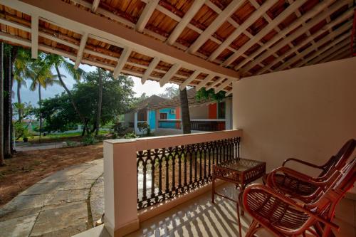 a porch with two chairs and a pergola at Papilio Beach Front Cottages-TBV in Baga