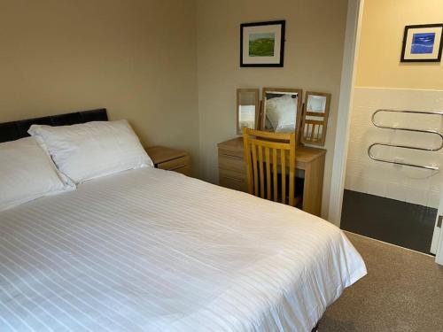 a bedroom with a large white bed and a desk at Corran Meadbh in Lahinch