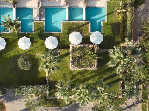an overhead view of a pool with umbrellas and palm trees at Amirandes, A Grecotel Resort to Live in Gouves