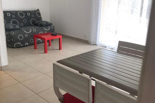 un salon avec un banc et un tabouret rouge dans l'établissement Comfortable nest just a stone's throw from the sea, au Pouliguen